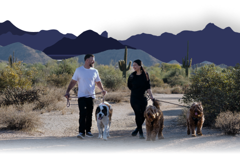 Couple walking three dogs in the Arizona desert